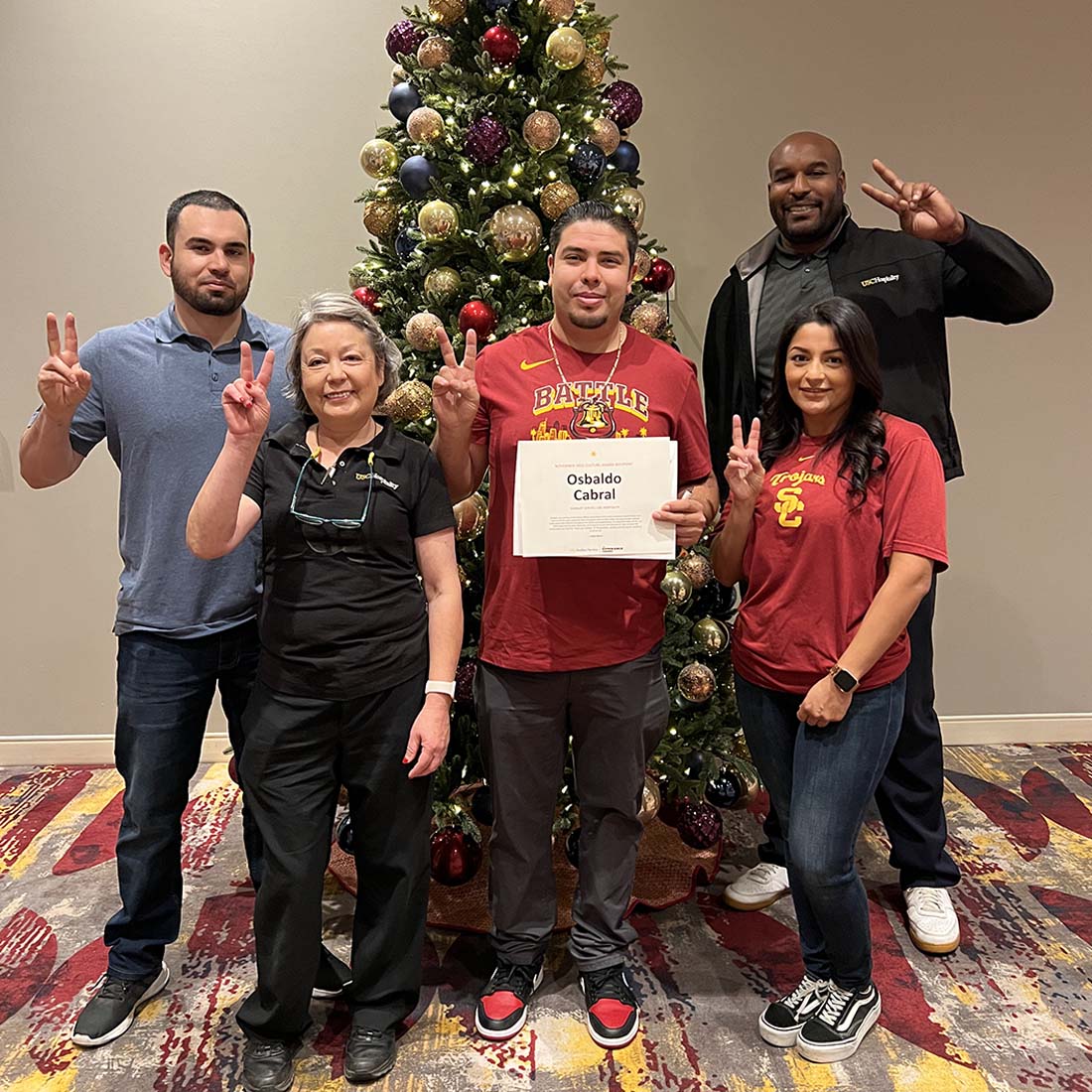 Employees posing in front of a Christmas tree.